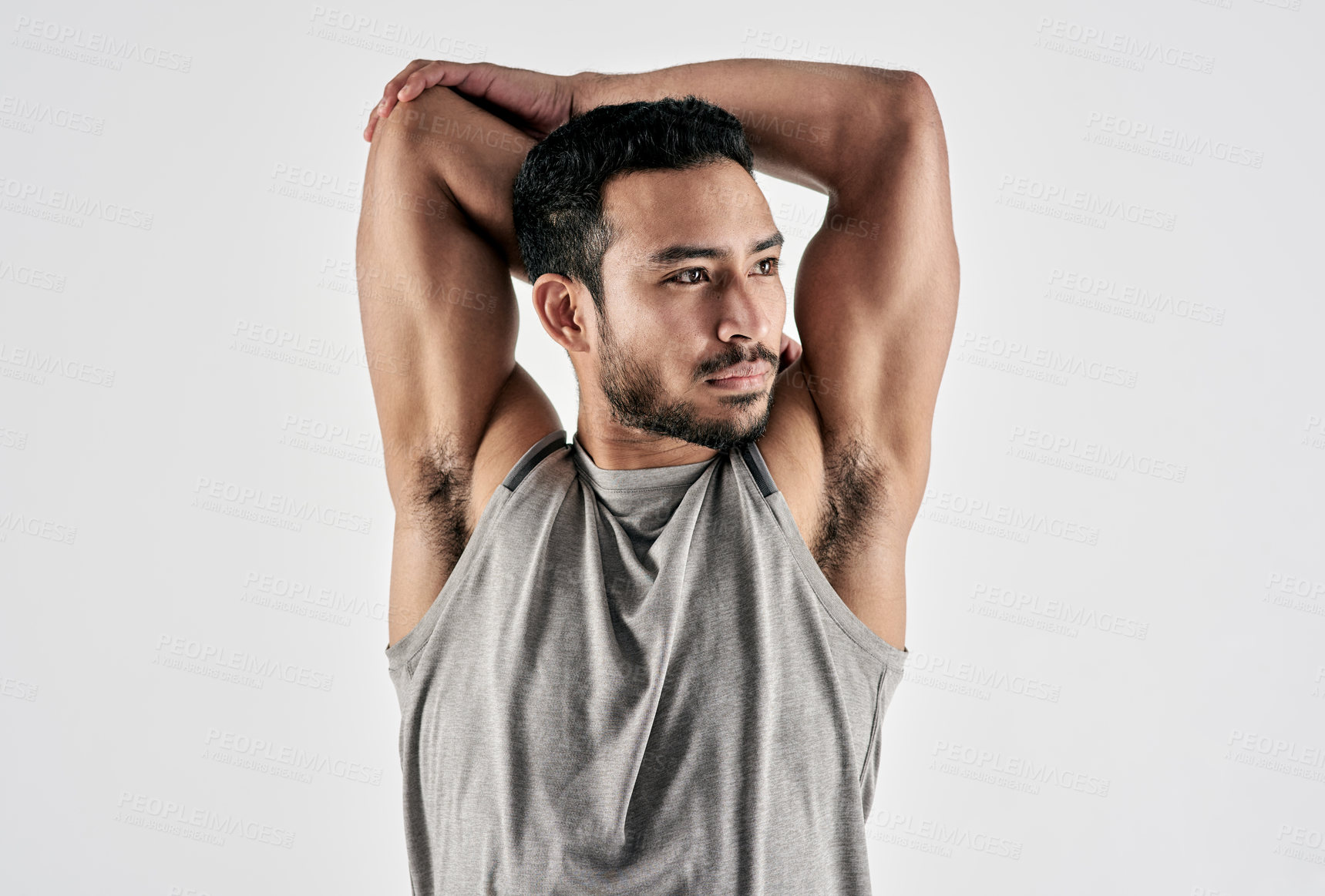Buy stock photo Studio shot of a muscular young man stretching his arms against a white background