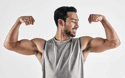 Buy stock photo Studio shot of a muscular young man flexing his biceps against a white background