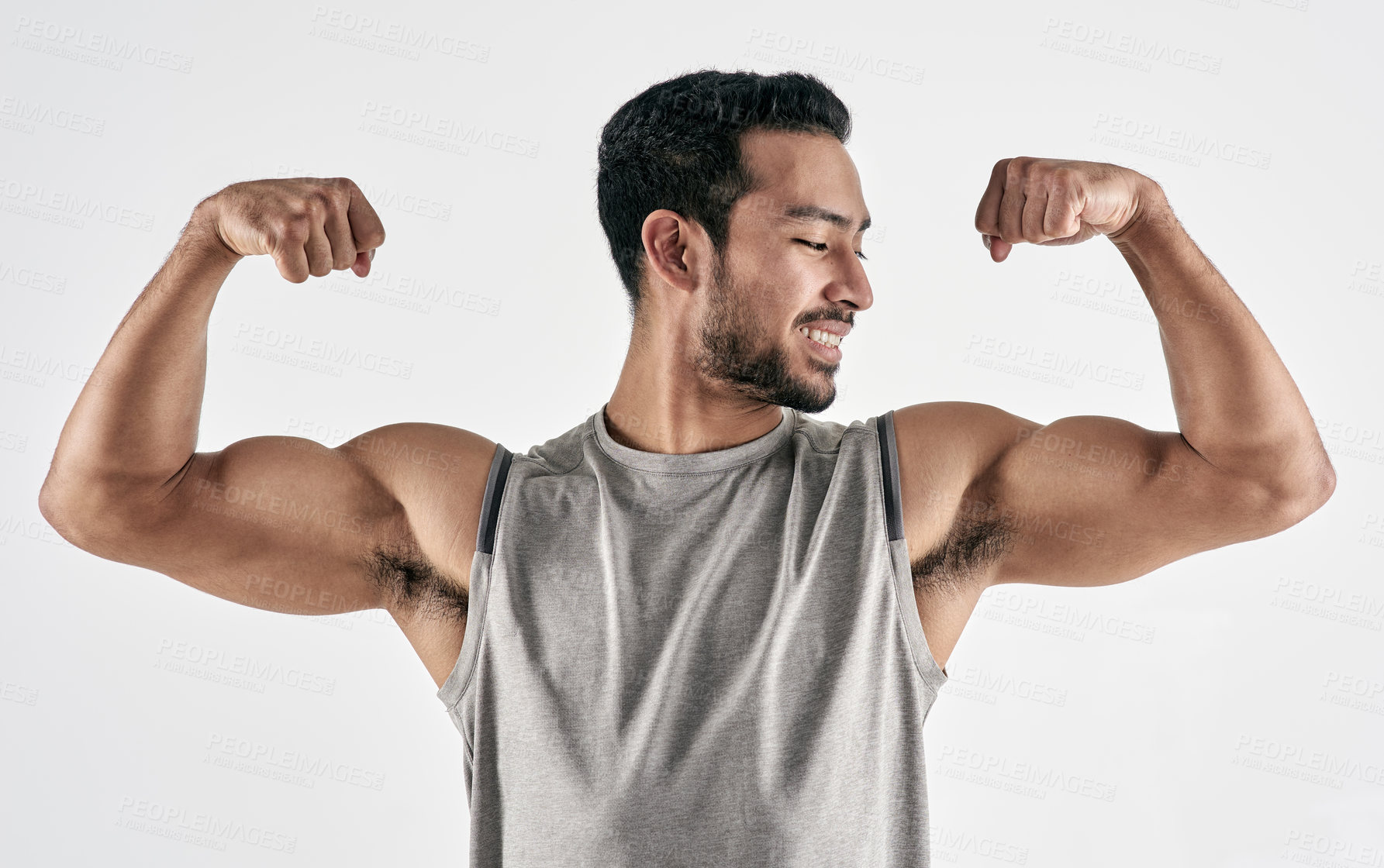 Buy stock photo Studio shot of a muscular young man flexing his biceps against a white background