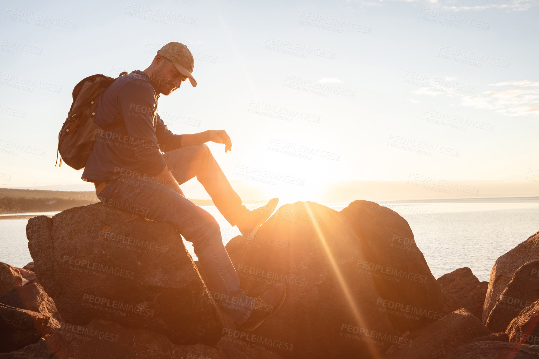 Buy stock photo Shot of a man wearing his backpack while out for a hike on a coastal trail