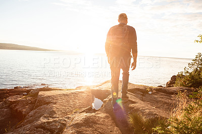 Buy stock photo Shot of a man wearing his backpack while out for a hike on a coastal trail