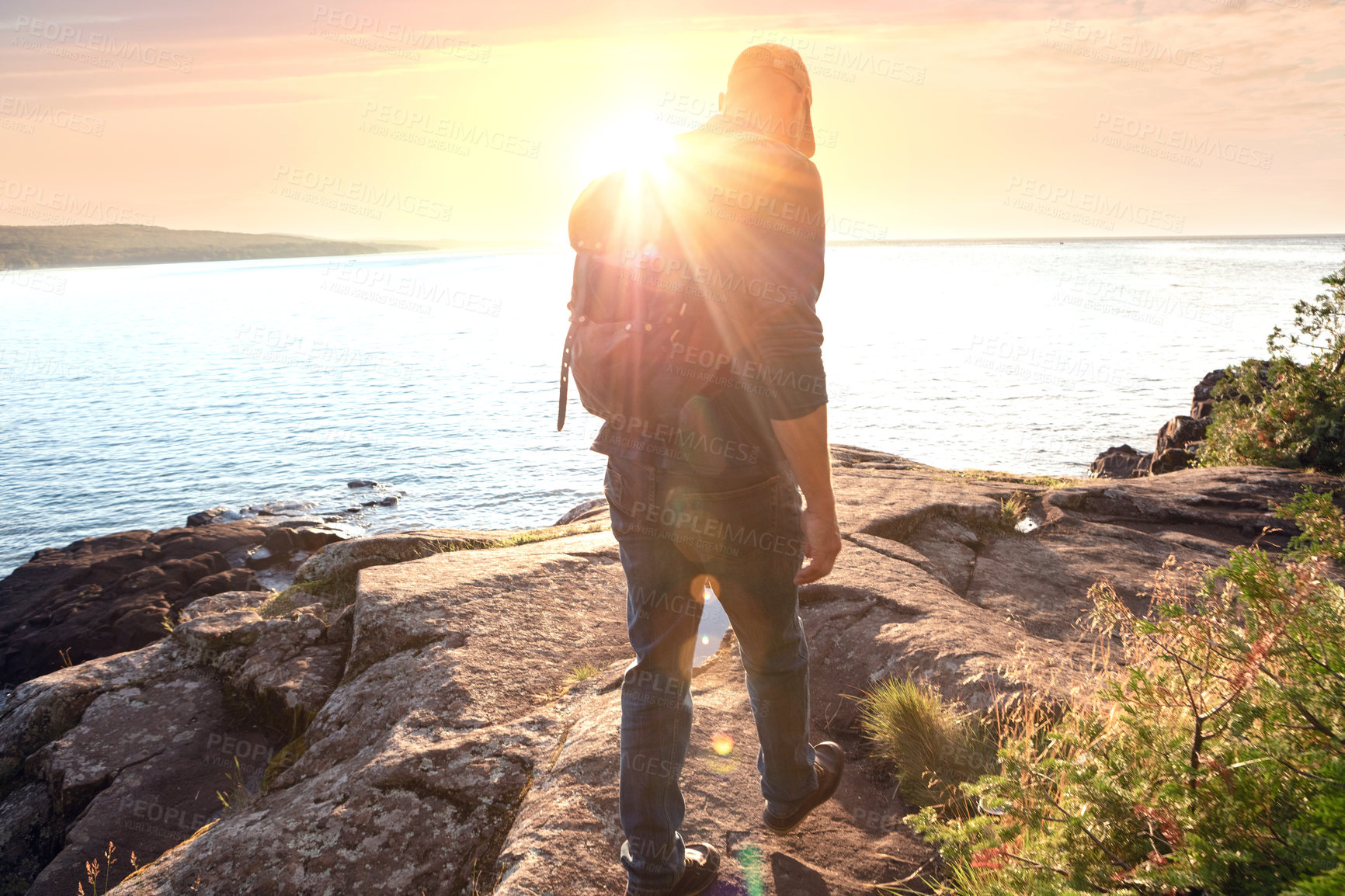 Buy stock photo Shot of a man wearing his backpack while out for a hike on a coastal trail