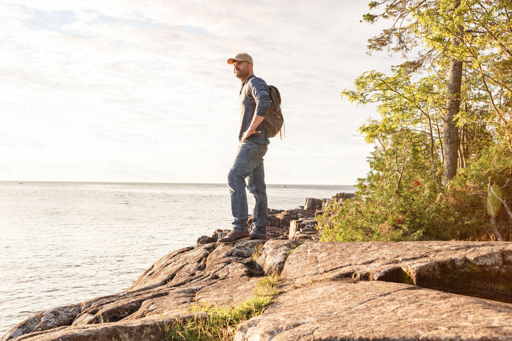 Buy stock photo Shot of a man wearing his backpack while out for a hike on a coastal trail