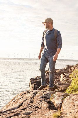 Buy stock photo Shot of a man wearing his backpack while out for a hike on a coastal trail