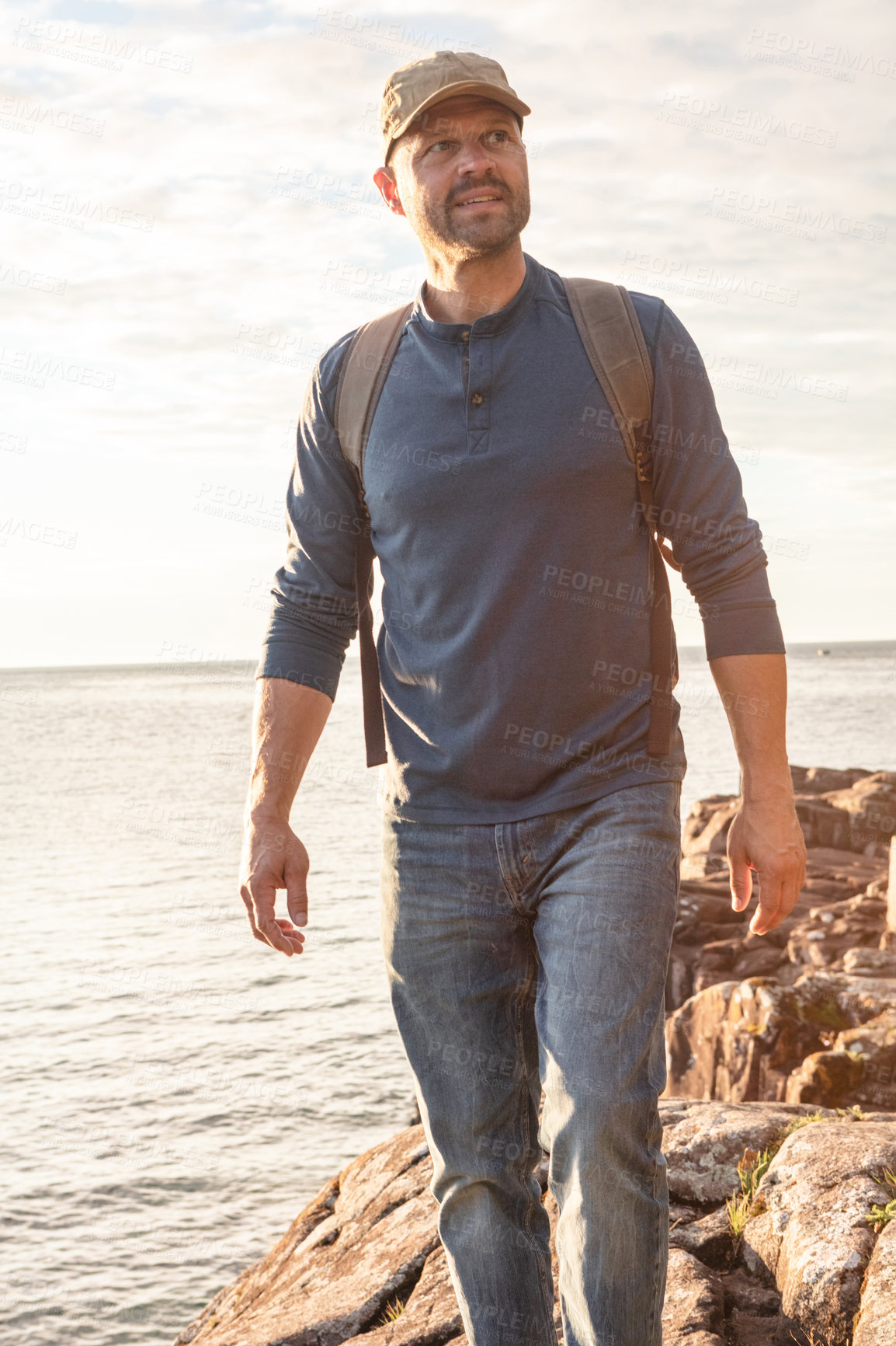 Buy stock photo Shot of a man wearing his backpack while out for a hike on a coastal trail