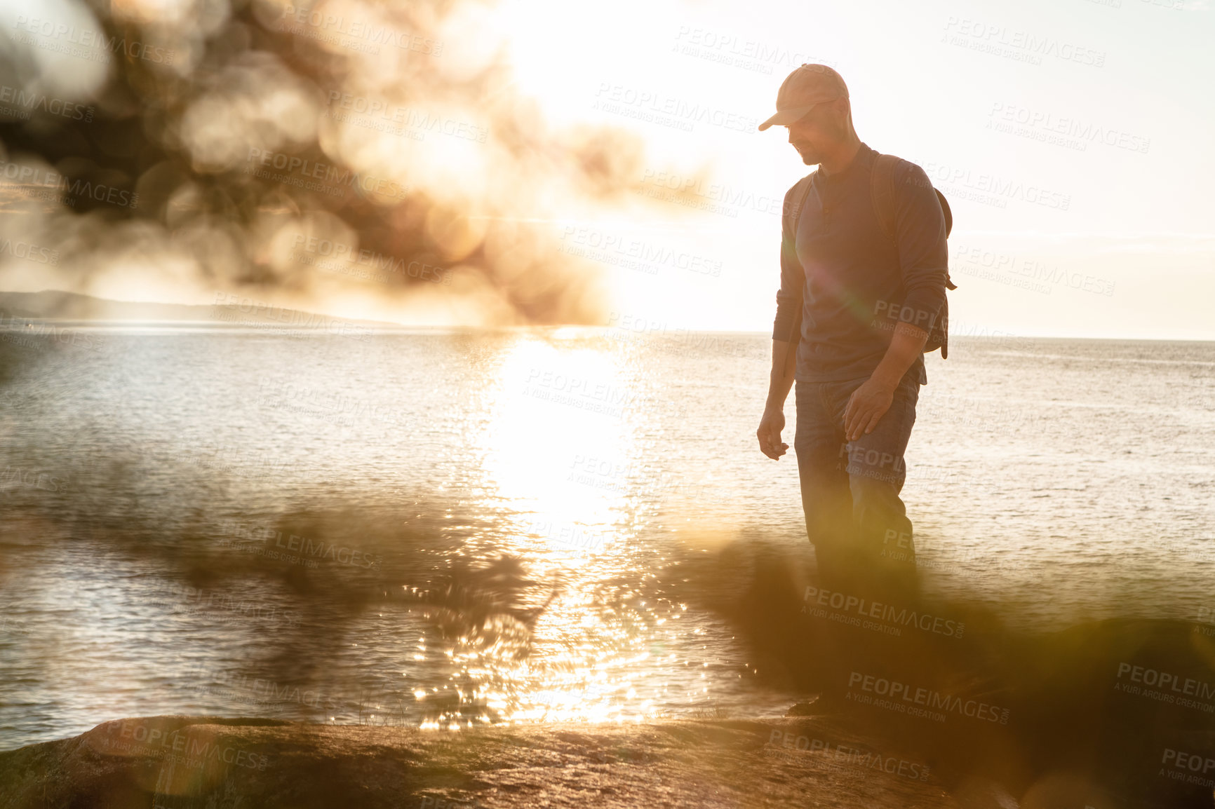 Buy stock photo Shot of a man wearing his backpack while out for a hike on a coastal trail