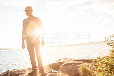 Buy stock photo Shot of a man wearing his backpack while out for a hike on a coastal trail