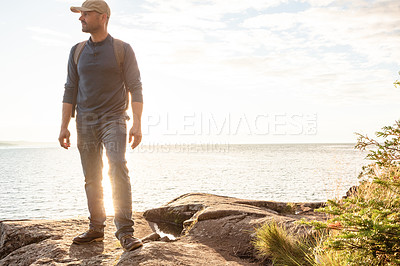 Buy stock photo Shot of a man wearing his backpack while out for a hike on a coastal trail