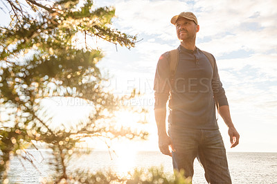 Buy stock photo Shot of a man wearing his backpack while out for a hike on a coastal trail