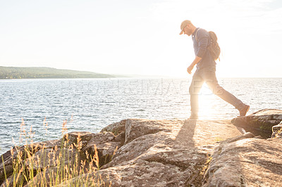 Buy stock photo Shot of a man wearing his backpack while out for a hike on a coastal trail