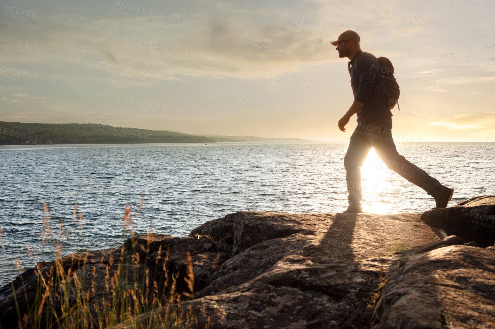 Buy stock photo Shot of a man wearing his backpack while out for a hike on a coastal trail