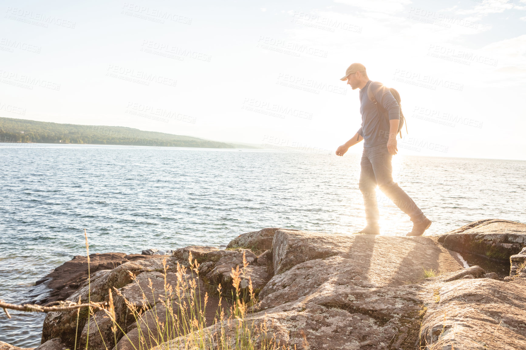 Buy stock photo Shot of a man wearing his backpack while out for a hike on a coastal trail