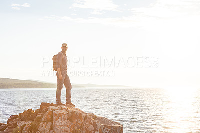 Buy stock photo Shot of a man wearing his backpack while out for a hike on a coastal trail