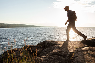 Buy stock photo Shot of a man wearing his backpack while out for a hike on a coastal trail