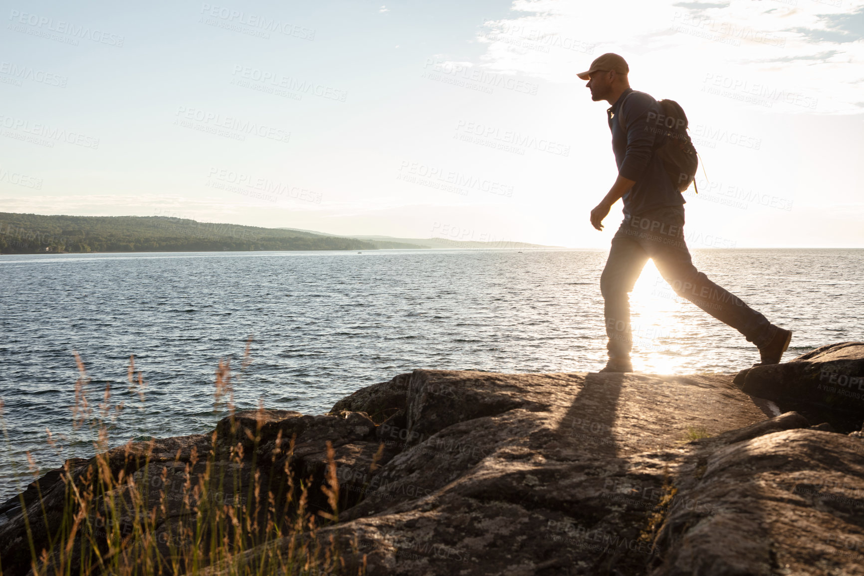 Buy stock photo Shot of a man wearing his backpack while out for a hike on a coastal trail