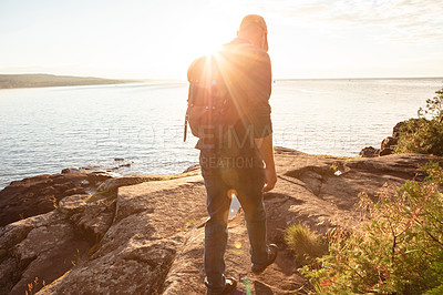 Buy stock photo Shot of a man wearing his backpack while out for a hike on a coastal trail