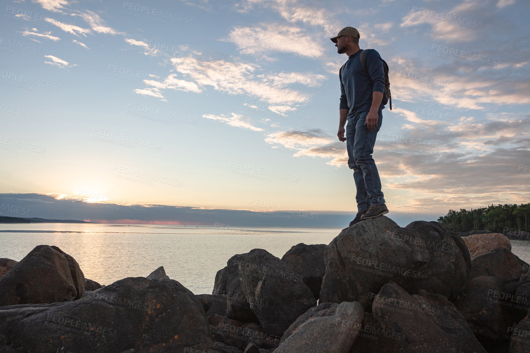 Buy stock photo Shot of a man wearing his backpack while out for a hike on a coastal trail