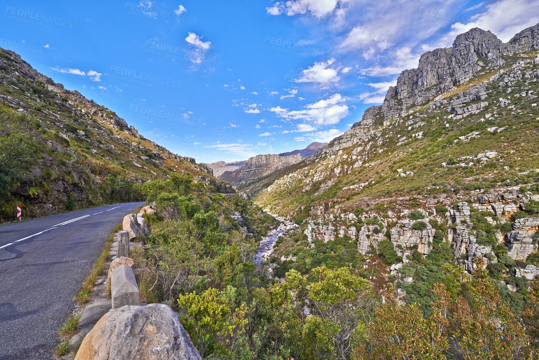 Buy stock photo Empty road in the mountains with a cloudy blue sky. Landscape of a countryside roadway for traveling on a mountain pass along a beautiful scenic nature drive with greenery and views of rolling hills