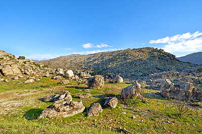 Buy stock photo A rocky mountainside landscape with green lush grass growing in an ecological rural environment. Beautiful field on rough terrain in nature with a scenic blue sky in the Western Cape during summer