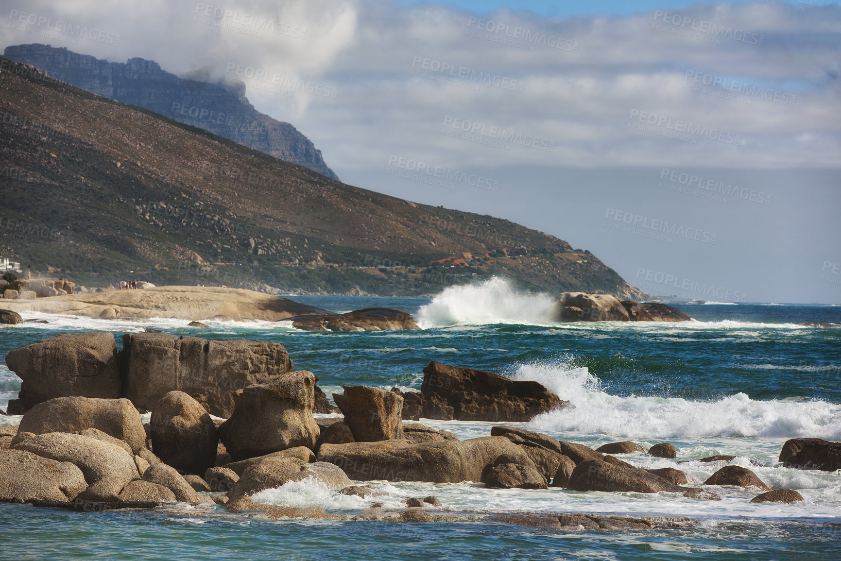 Buy stock photo Ocean view of waves crashing against boulders or rocks in the sea in Camps Bay, Cape Town in South Africa. Relaxed and calm landscape view of the sea and mountains against a cloudy overcast sky 