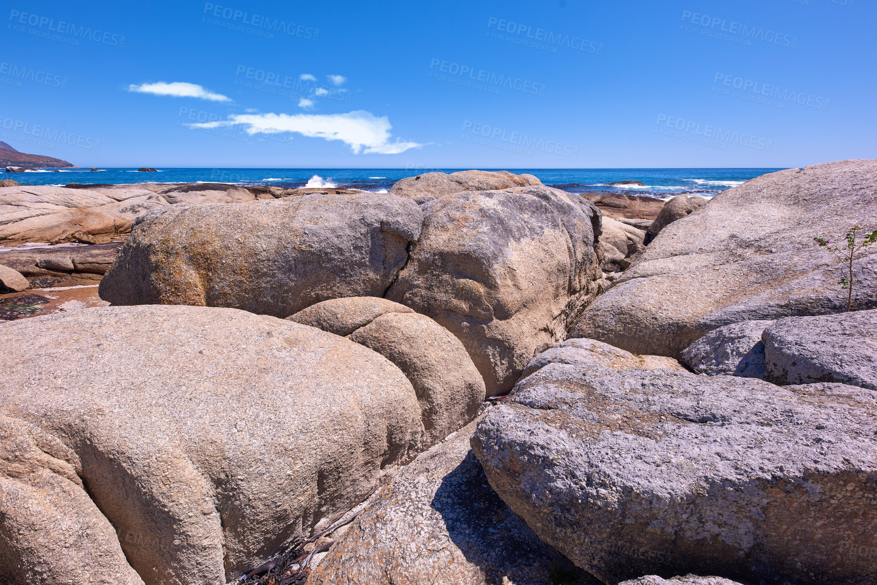 Buy stock photo Rocky coastline with the ocean and blue sky with copyspcae in the background. Stunning nature landscape or seascape of rocks. Boulders or big natural stones in the sea with beautiful rough textures