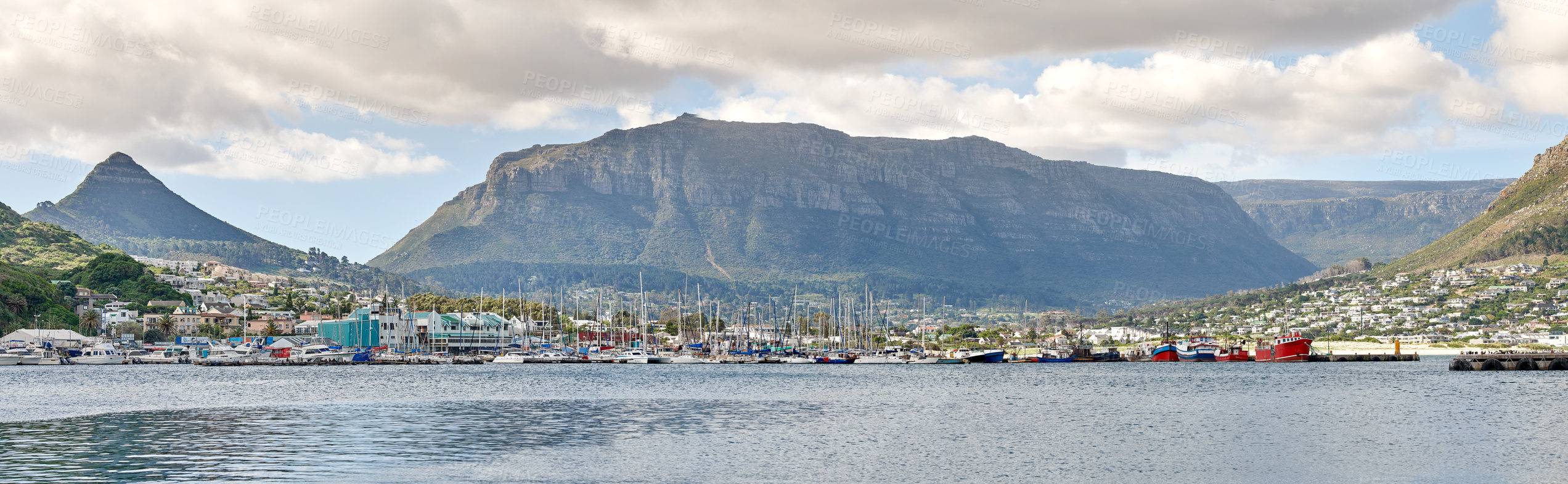 Buy stock photo Beautiful view of the ocean and cloudy blue sky with Table mountain in the background. Peaceful ocean seascape with copy space and urban buildings close to the harbor in Cape Town, South Africa