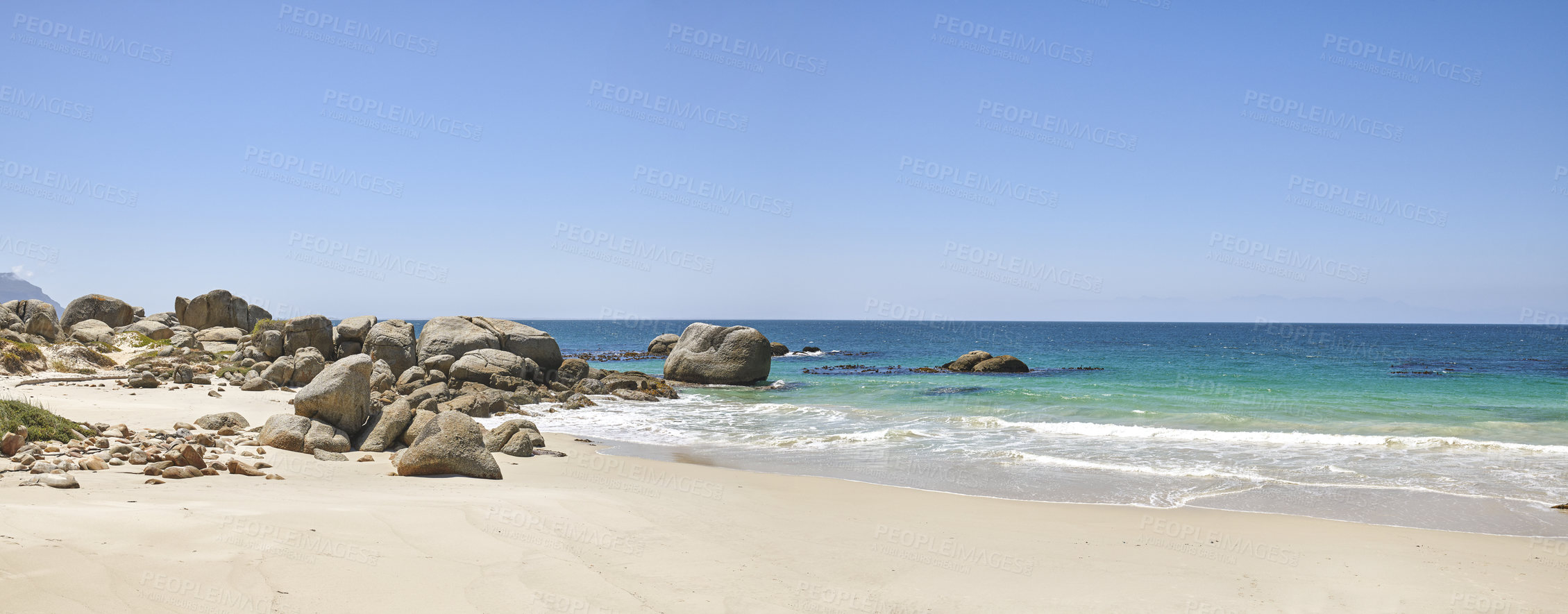 Buy stock photo Calm beach with white sand on a rocky natural seaside environment in a popular getaway location for a holiday in Cape town. Landscape of the ocean on a sunny day with blue sky and copy space