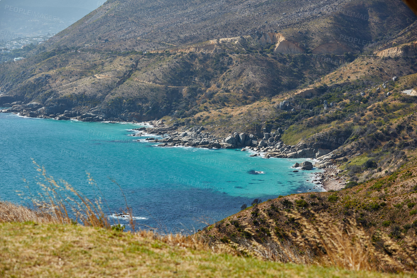 Buy stock photo A beautiful sea landscape near a mountain with lush green plants growing outdoors in nature. Peaceful and scenic view of the ocean with turquoise water on summer afternoon in Cape Town, South Africa