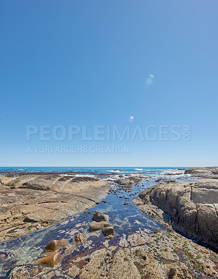 Buy stock photo Copy space at sea with a clear blue sky background and rocky coast in Camps Bay, Cape Town, South Africa. Boulders at a beach shore across a majestic ocean. Scenic landscape for a summer holiday