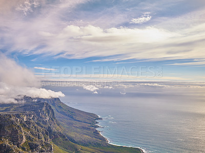 Buy stock photo Aerial view of a calm ocean and mountains with a blue cloudy sky background and copy space. Stunning nature landscape of the sea and horizon from Table Mountain tourism destination in Cape Town