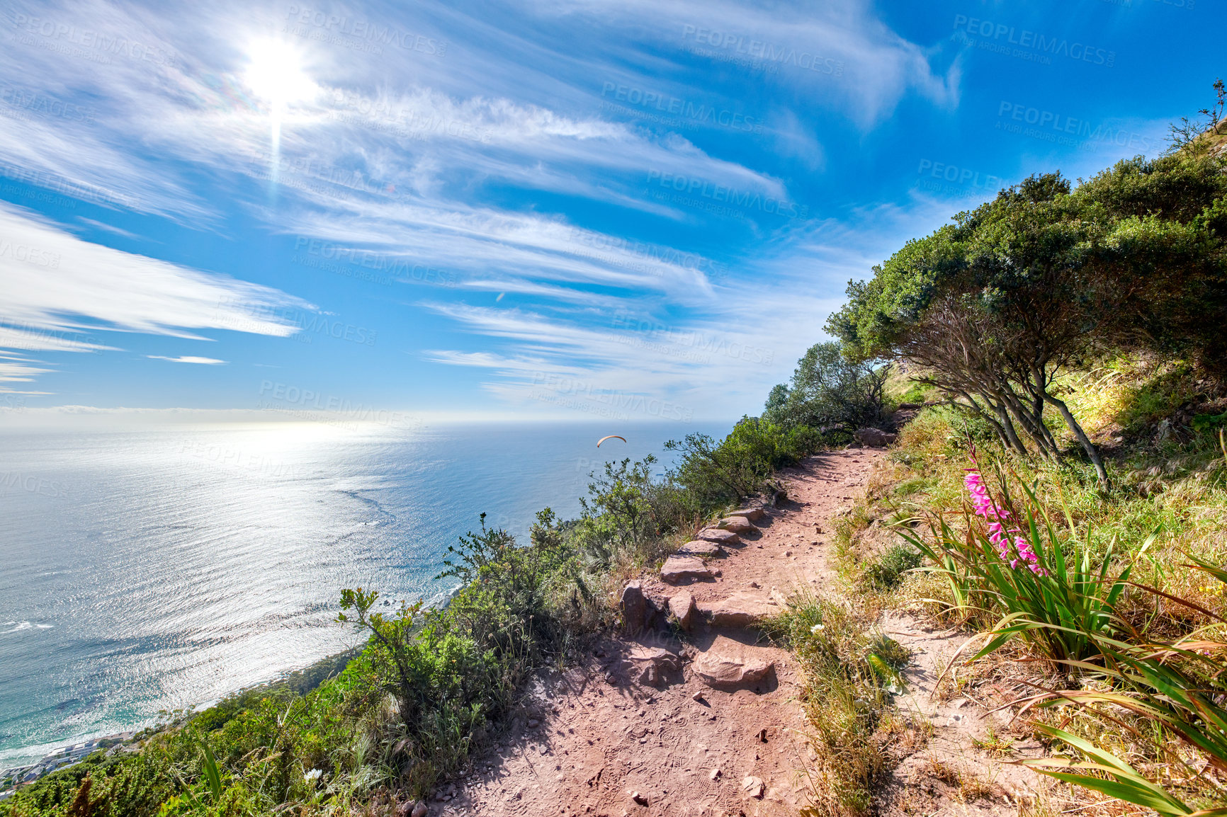 Buy stock photo Copy space with scenic coast and rocky mountain slope with cloudy blue sky background. Rugged landscape of plants growing on a cliff by the sea with hiking trails to explore in Cape Town South Africa