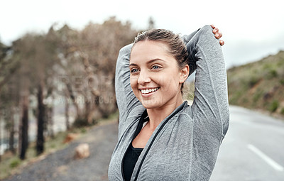 Buy stock photo Shot of a sporty young woman stretching her arms while exercising outdoors