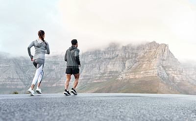 Buy stock photo Rearview shot of a sporty young man and woman running together outdoors