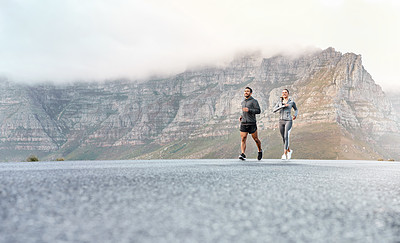 Buy stock photo Shot of a sporty young man and woman running together outdoors