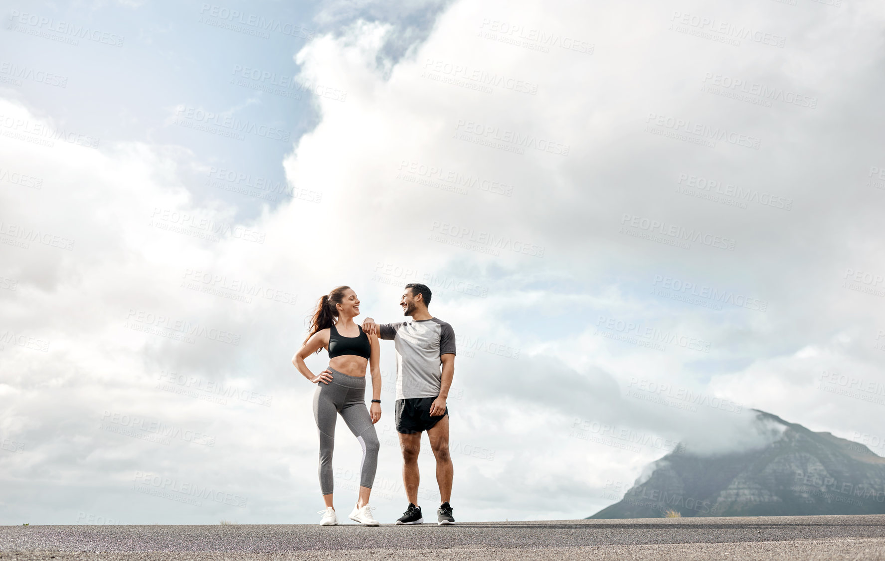 Buy stock photo Shot of a sporty young man and woman exercising together outdoors