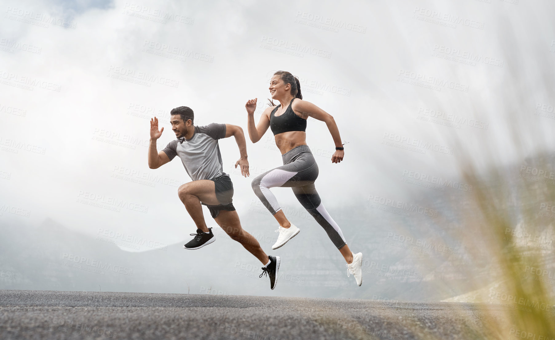 Buy stock photo Shot of a sporty young man and woman running together outdoors