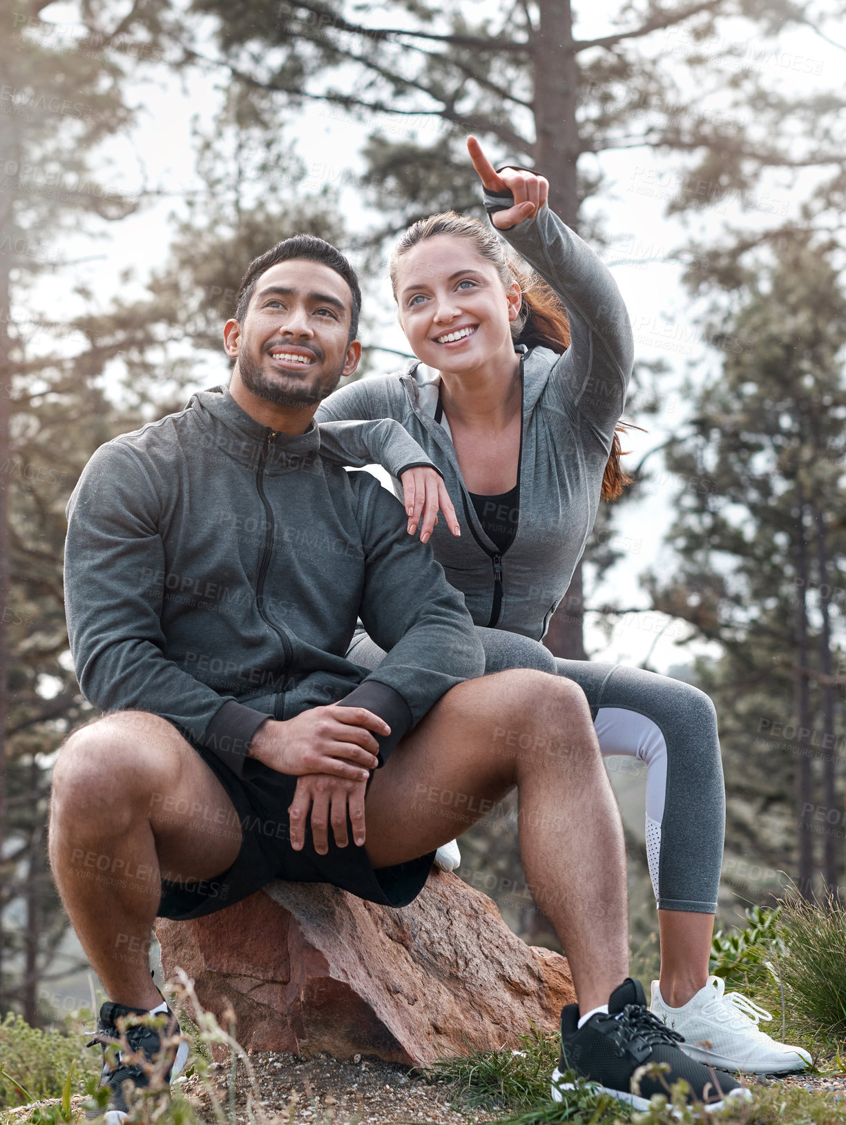 Buy stock photo Shot of a sporty young man and woman taking a break while exercising outdoors