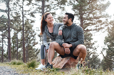 Buy stock photo Shot of a sporty young man and woman taking a break while exercising outdoors