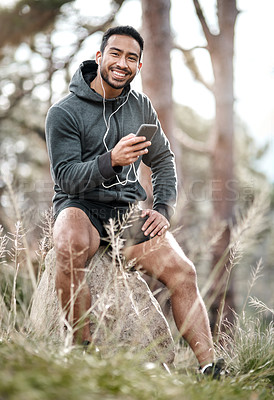 Buy stock photo Portrait of a sporty young man wearing earphones while using a cellphone outdoors