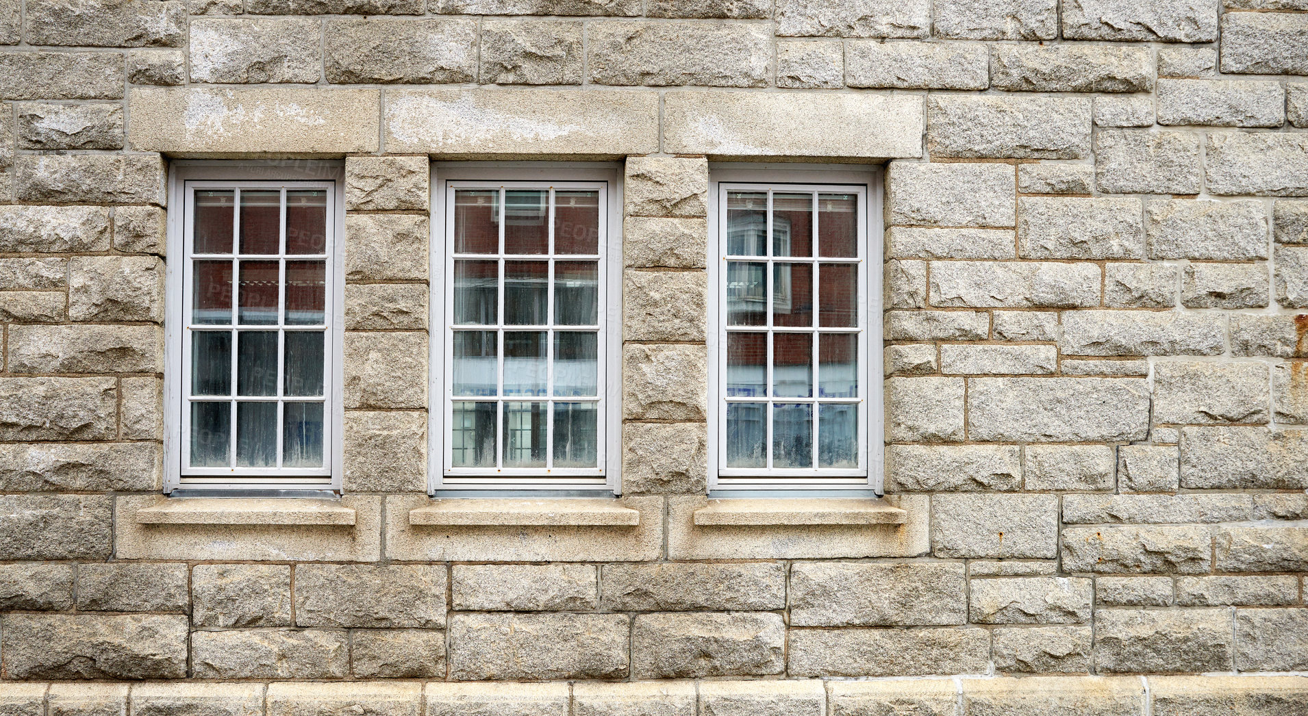 Buy stock photo Old windows on the side of a brown stone building for architectural detail. Closeup of the cultural and textured design on a brick wall outside of a house, school or church in a small town 