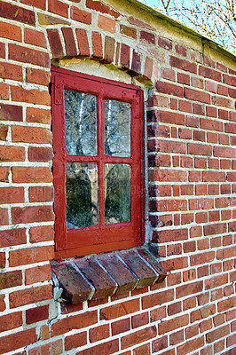 Buy stock photo Old dirty window in a red brick home. Ancient casement with red wood frame in a historic building with lumpy paint texture. Exterior details of a windowsill in a traditional town or village 