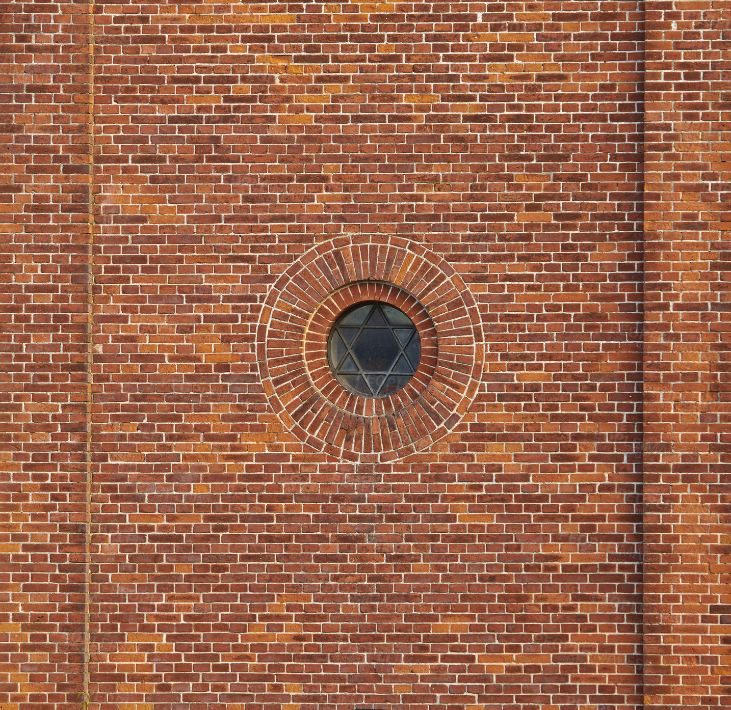 Buy stock photo Wall of a jewish synagogue with round window on an old red brick house outside. Small metal frame on historic temple building with Star of David design and architectural background with copy space