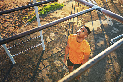 Buy stock photo Shot of a young man working out at the outdoor gym at the park