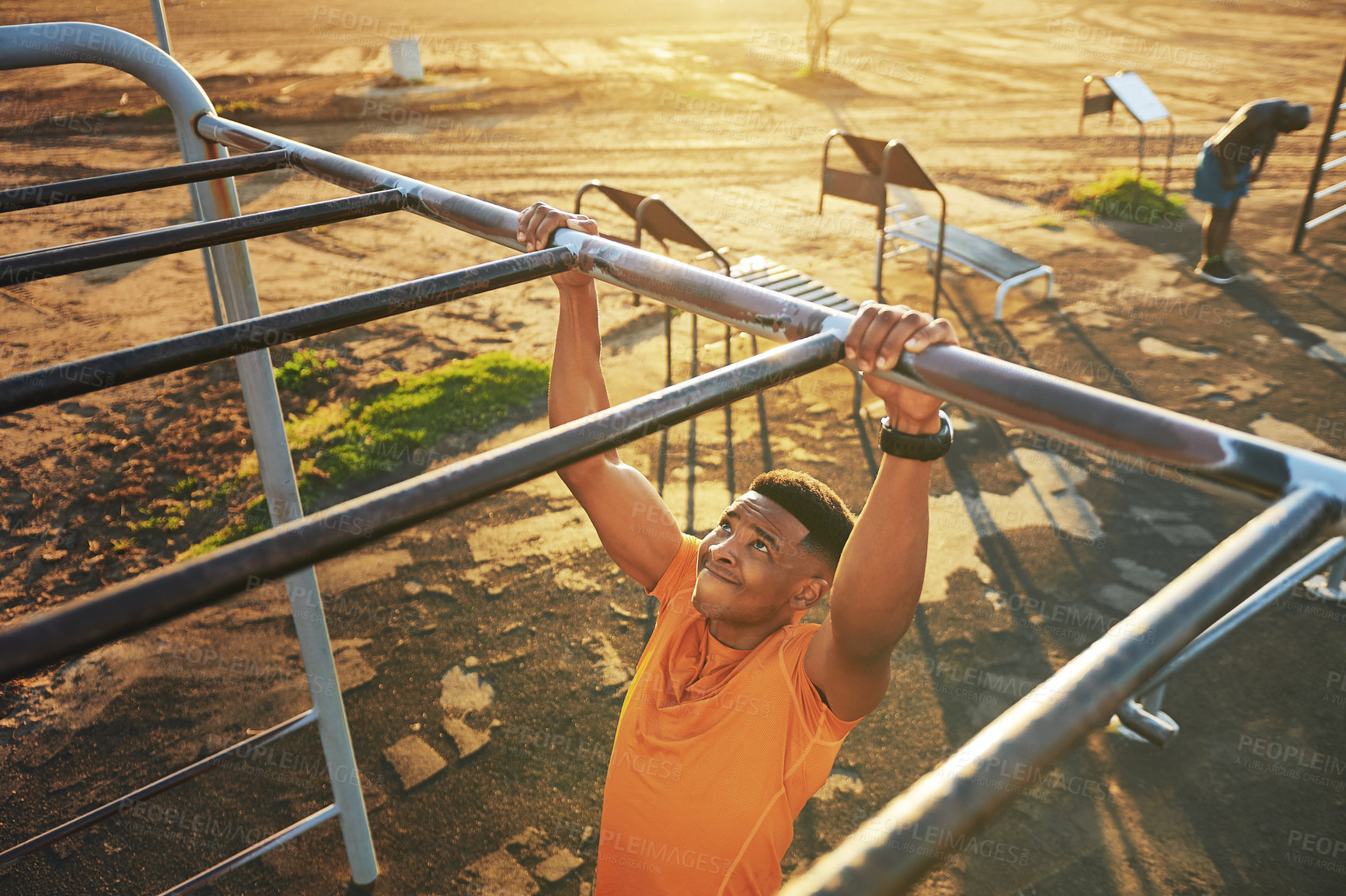 Buy stock photo Shot of a young man working out at the outdoor gym at the park