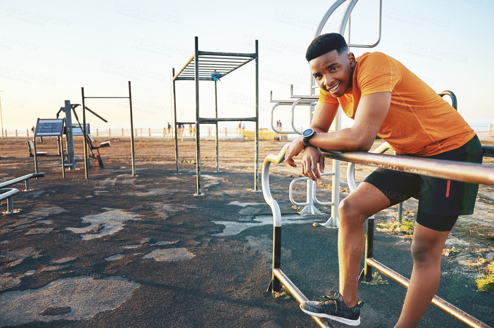 Buy stock photo Shot of a young man working out at the outdoor gym at the park