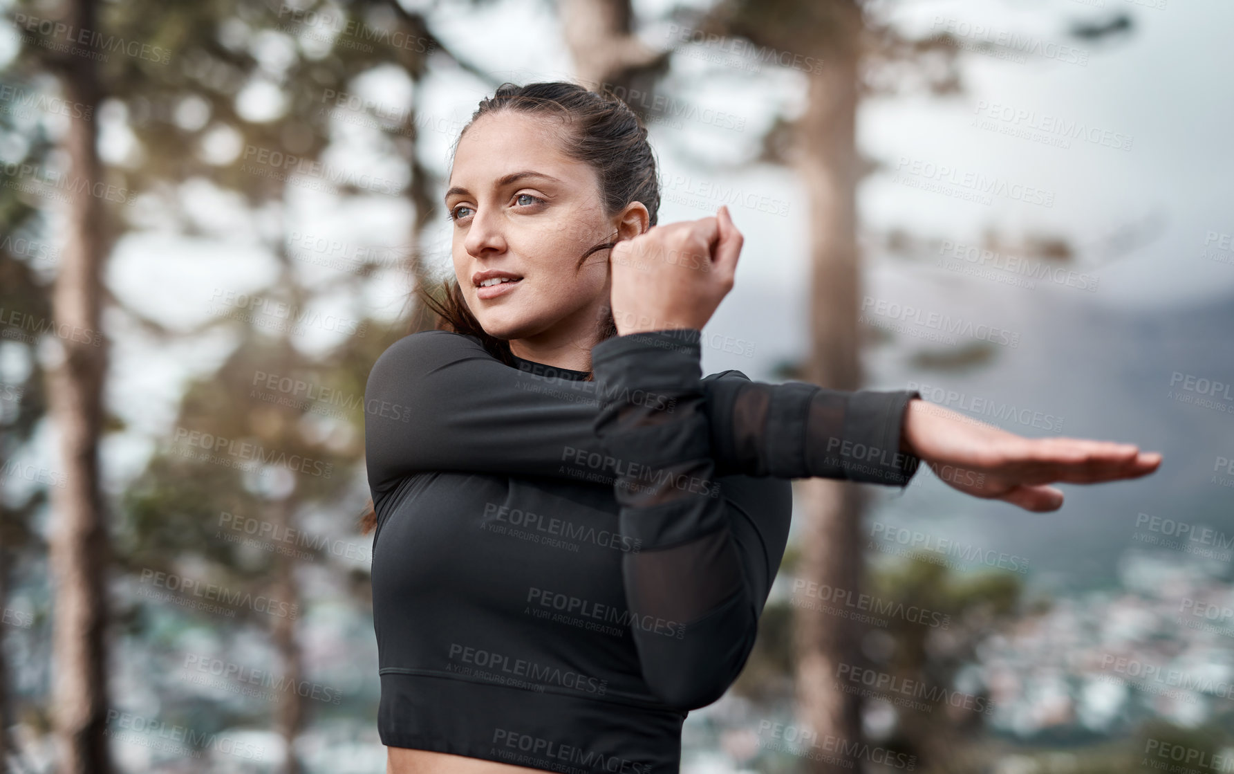 Buy stock photo Cropped shot of an attractive young woman stretching before exercising outdoors alone
