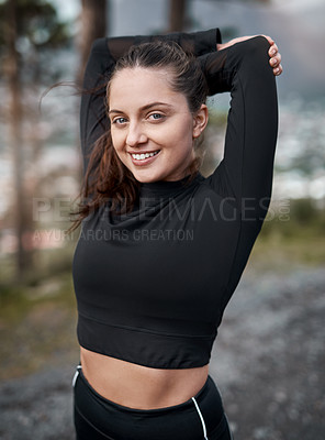Buy stock photo Cropped portrait of an attractive young woman stretching before exercising outdoors alone