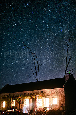 Buy stock photo Shot of a house in the countryside on a dark starry night