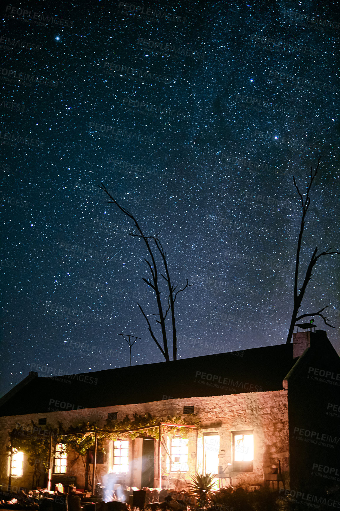 Buy stock photo Shot of a house in the countryside on a dark starry night