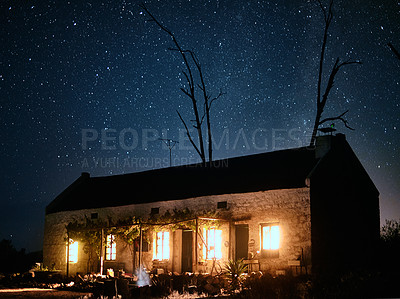 Buy stock photo Shot of a house in the countryside on a dark starry night